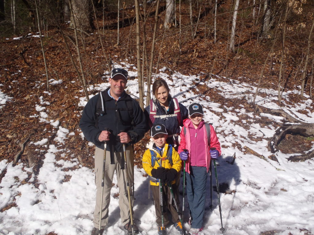 A family poses for a picture in the snow.