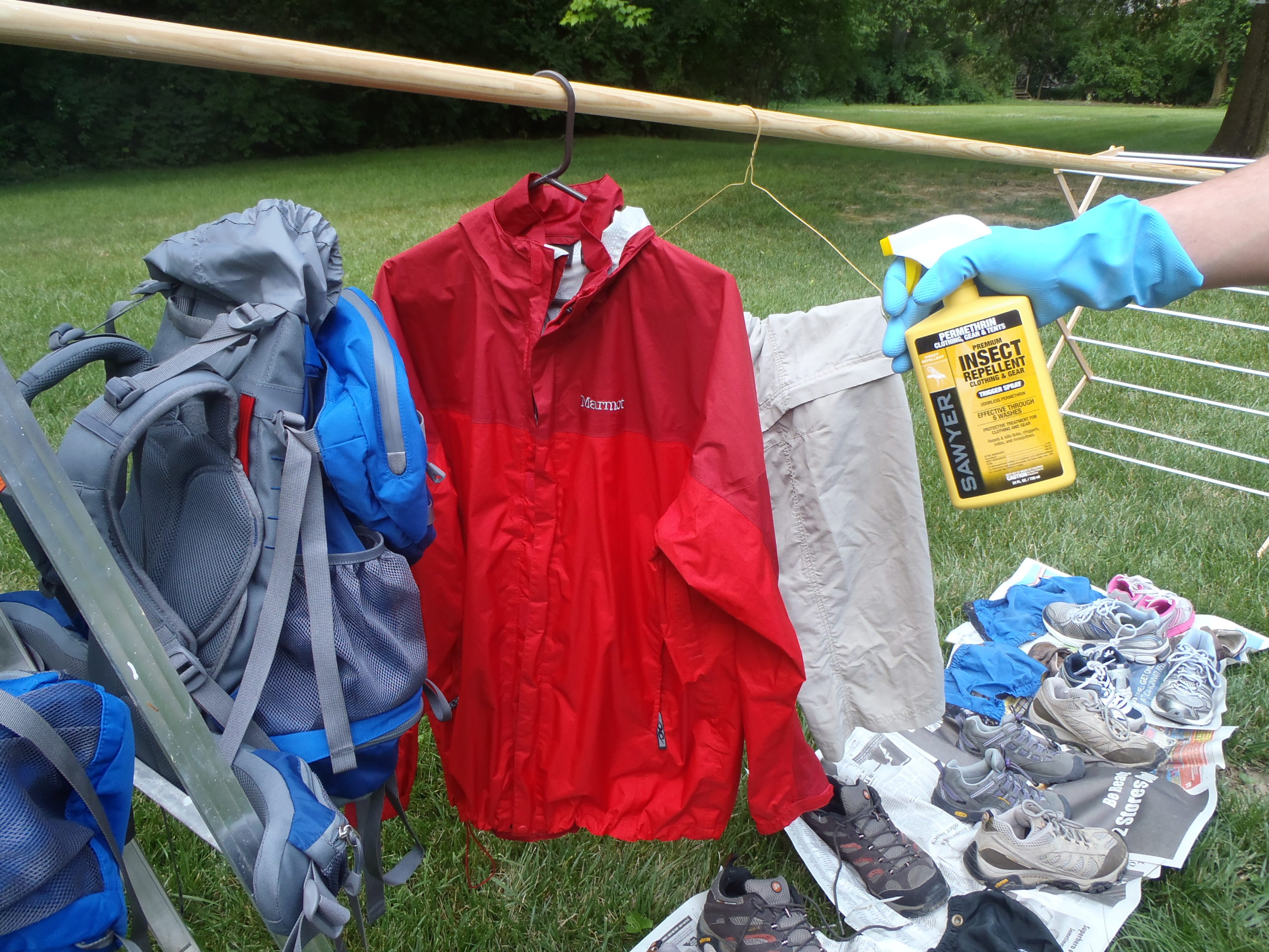 A person holding up a spray bottle next to some clothes.